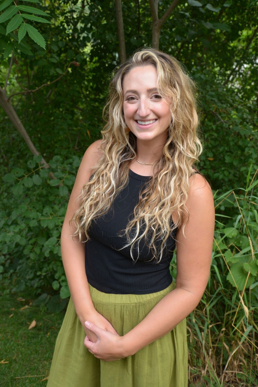 Sarah Ahrens smiling outdoors in a black top and green skirt